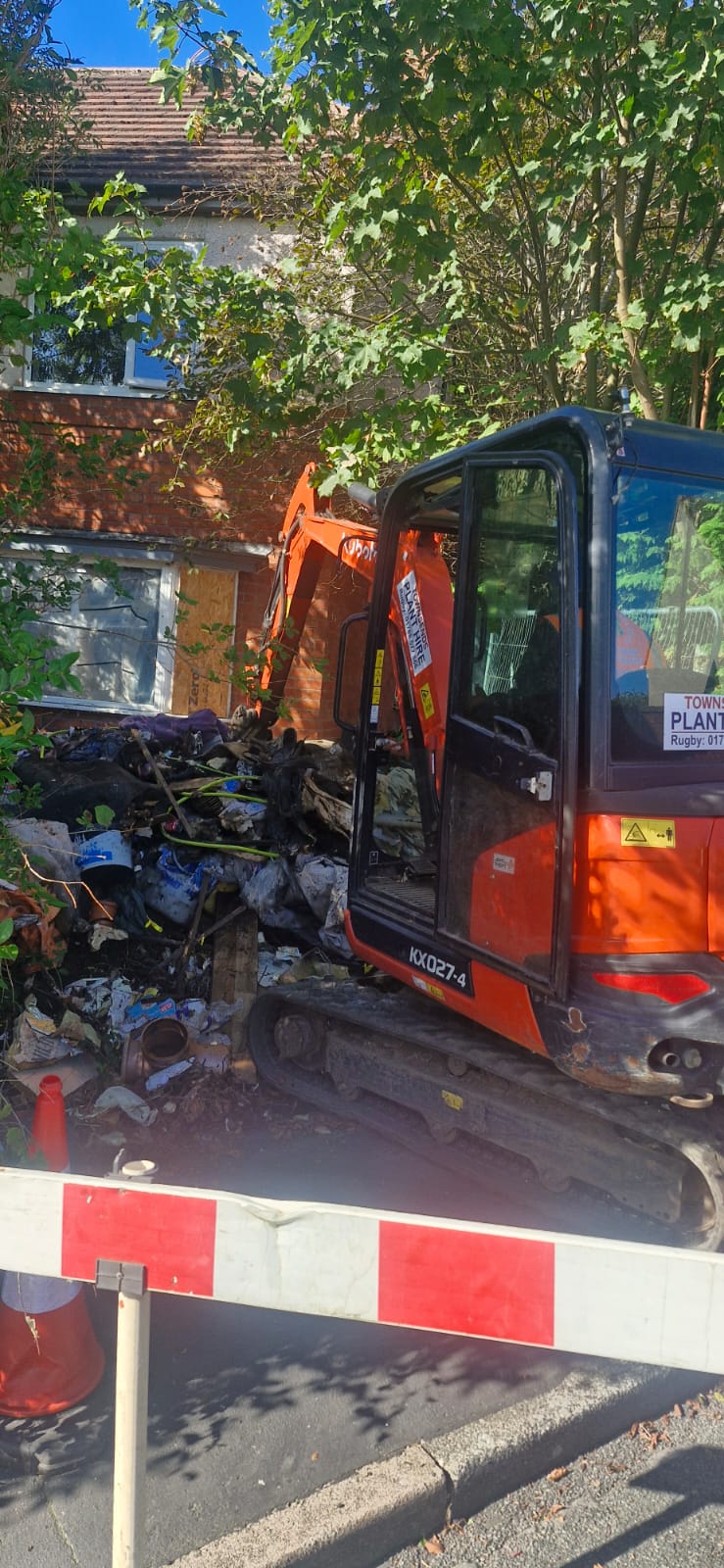 In progress: hired mini digger clearing a large waste pile at a house