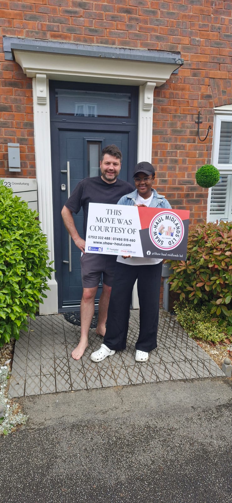 Customers at their front door with a Shaw Haul move sign