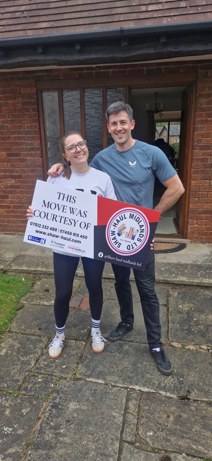 Happy customers holding a Shaw Haul move sign outside their home