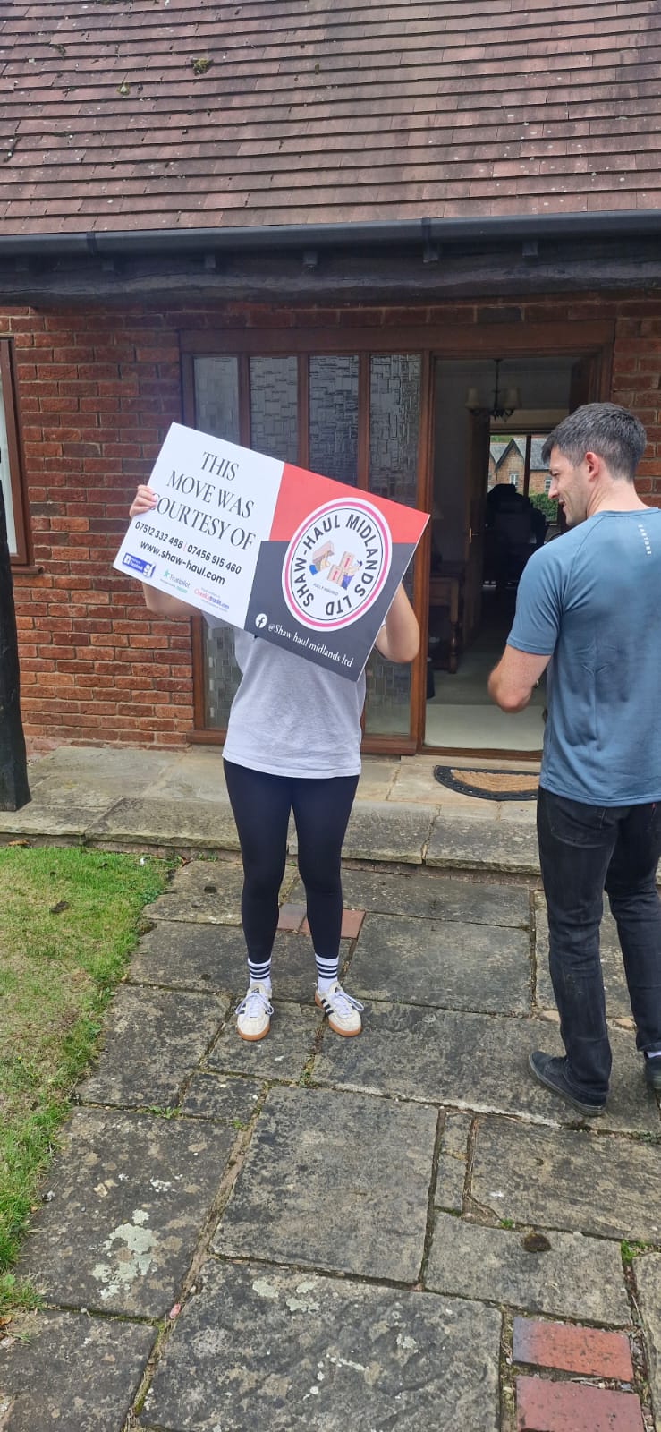 Customer holding up the Shaw Haul move sign outside their home
