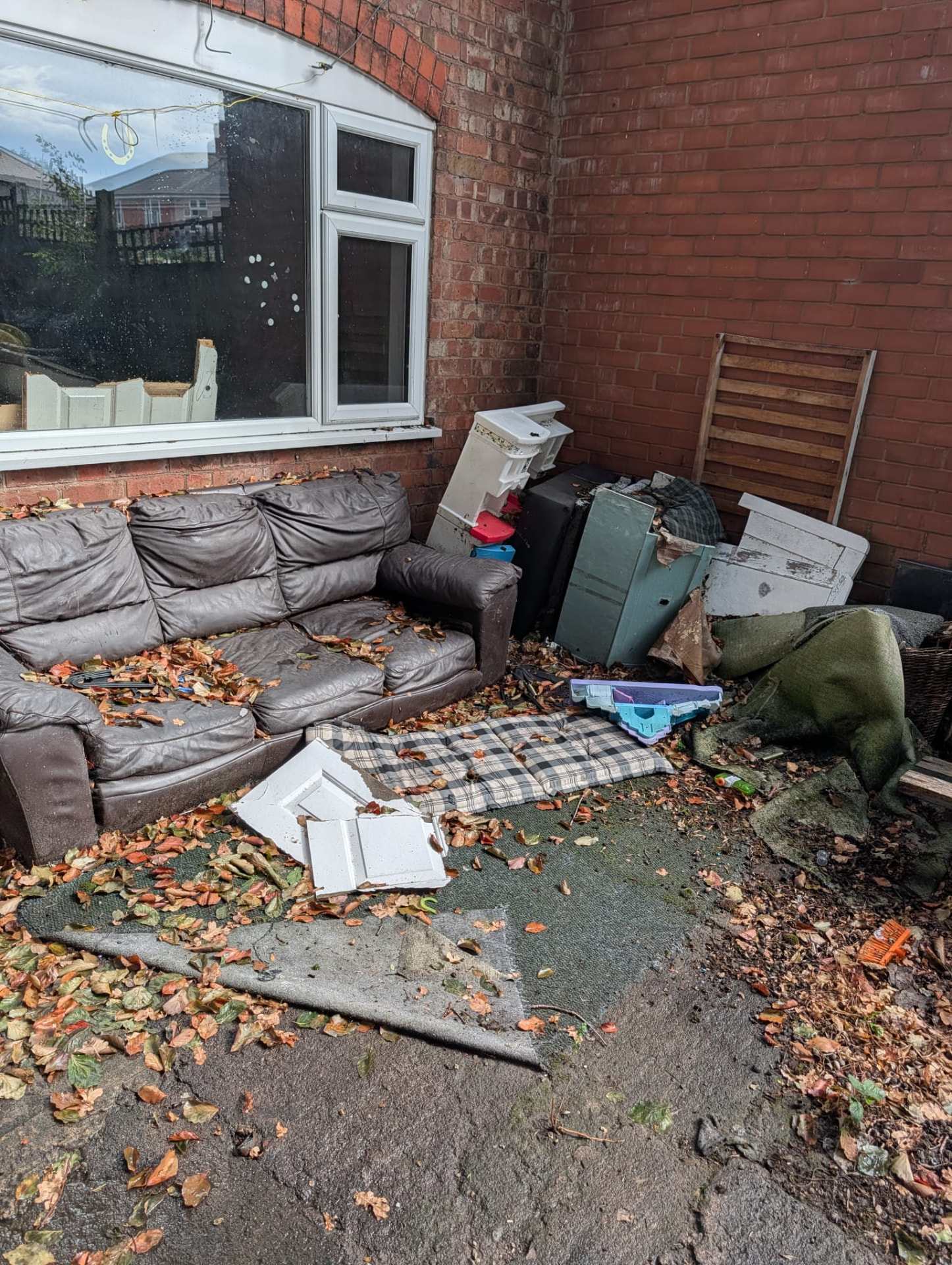 Before: old sofa and furniture piled against a house wall