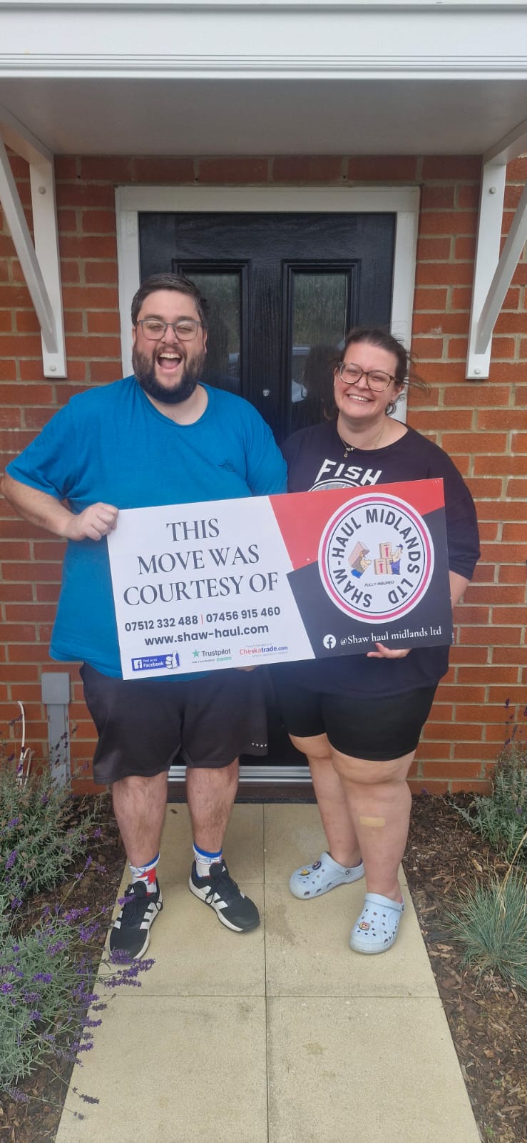 Delighted couple celebrating their move with the Shaw Haul sign