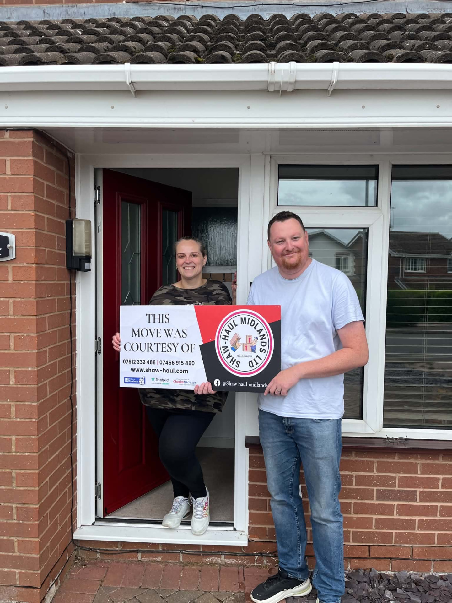 Couple holding the Shaw Haul move sign in their doorway