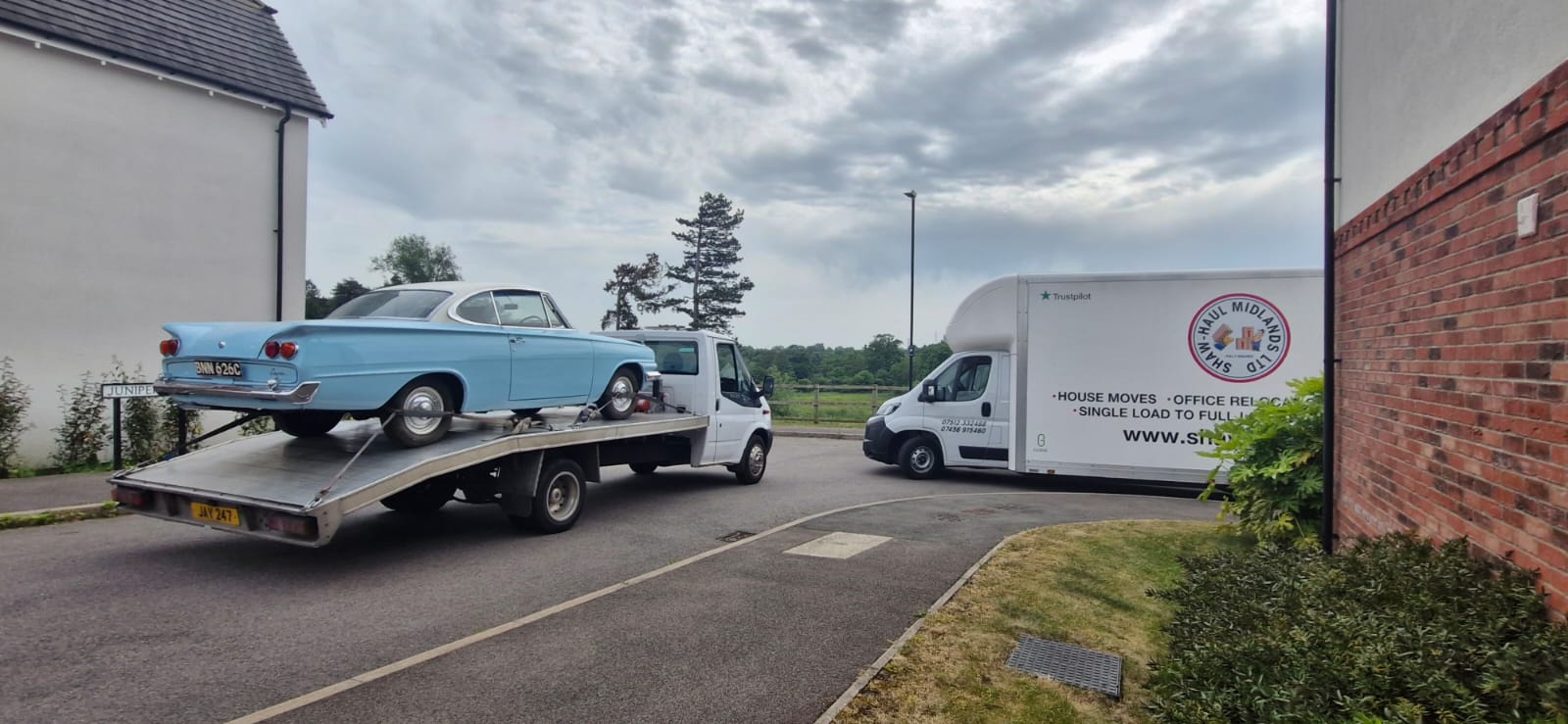 A classic car secured for transport on a recovery truck.