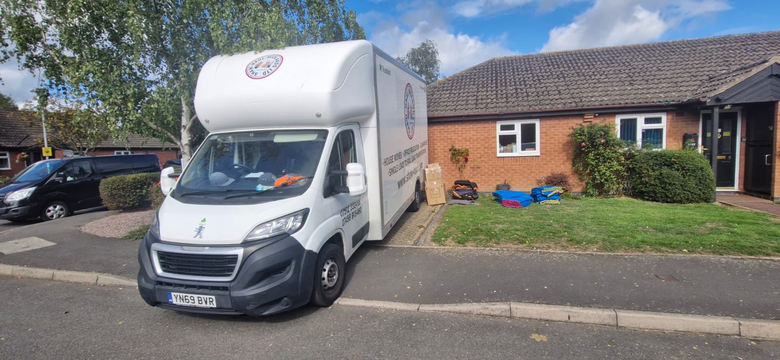Shaw Haul Luton van on a bungalow driveway with boxes and blankets on the lawn