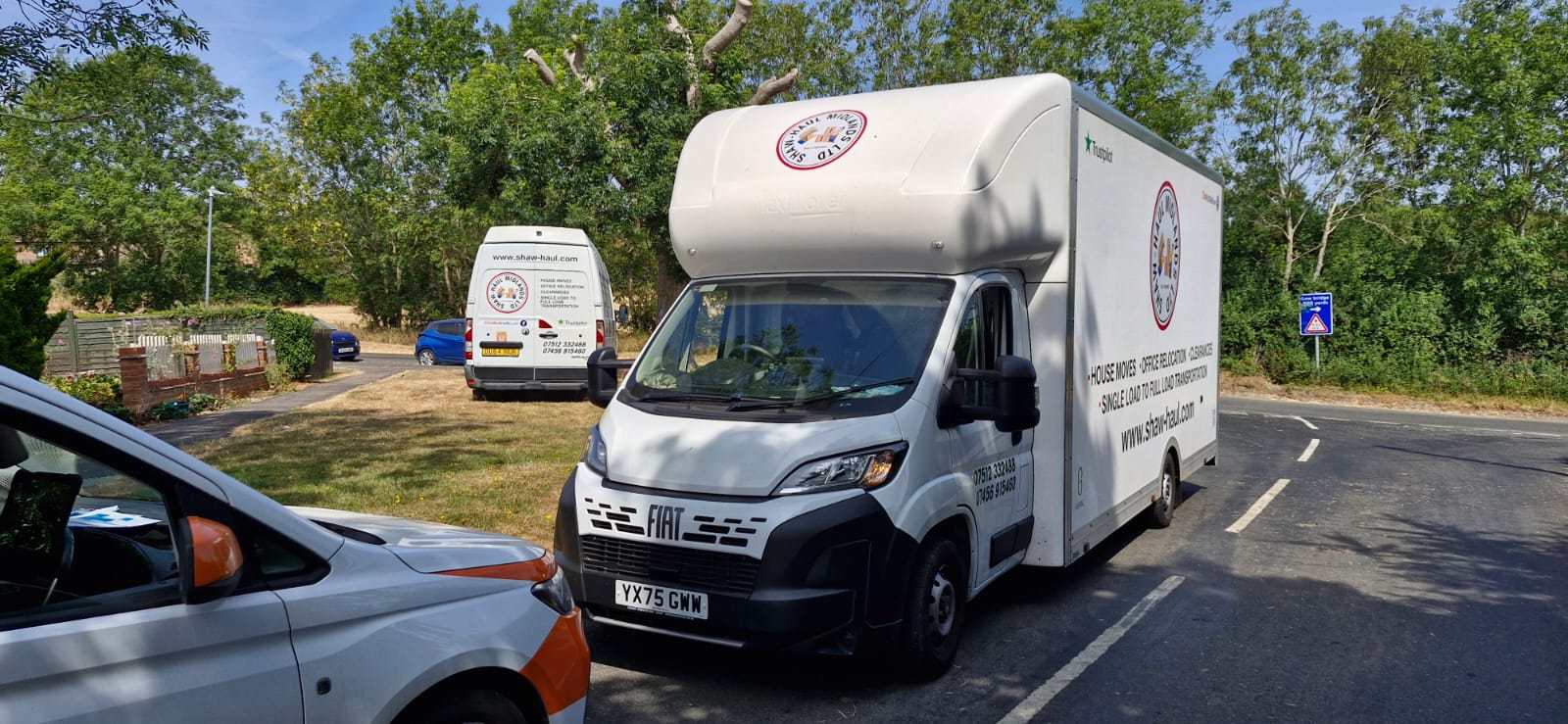 Shaw Haul Luton and panel van parked by a village green