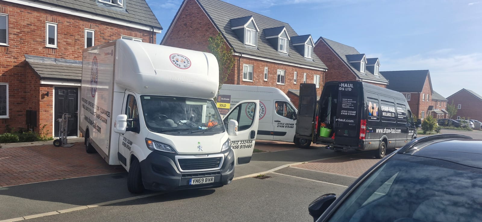 Three Shaw Haul vans working together on a new-build street