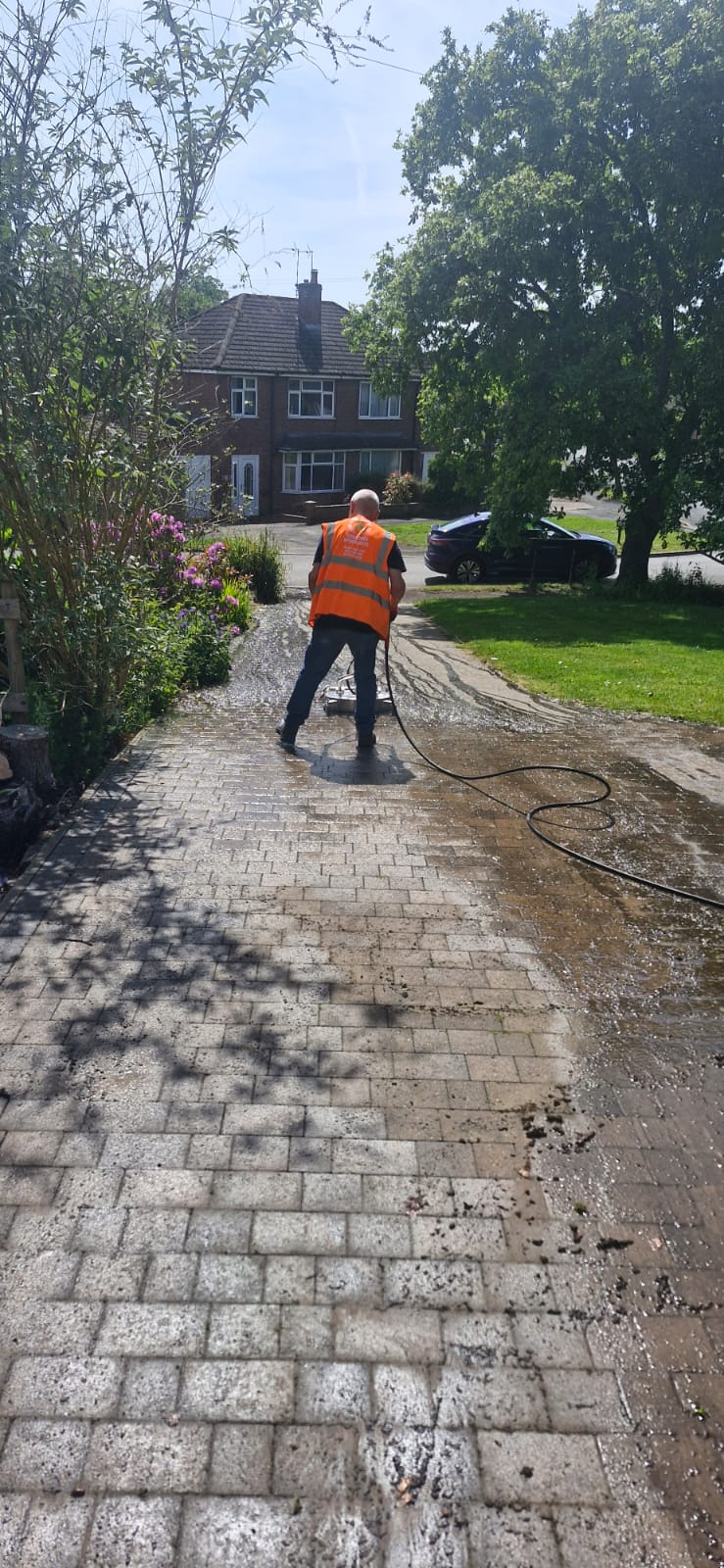 A Shaw Haul team member pressure washing a block-paved driveway